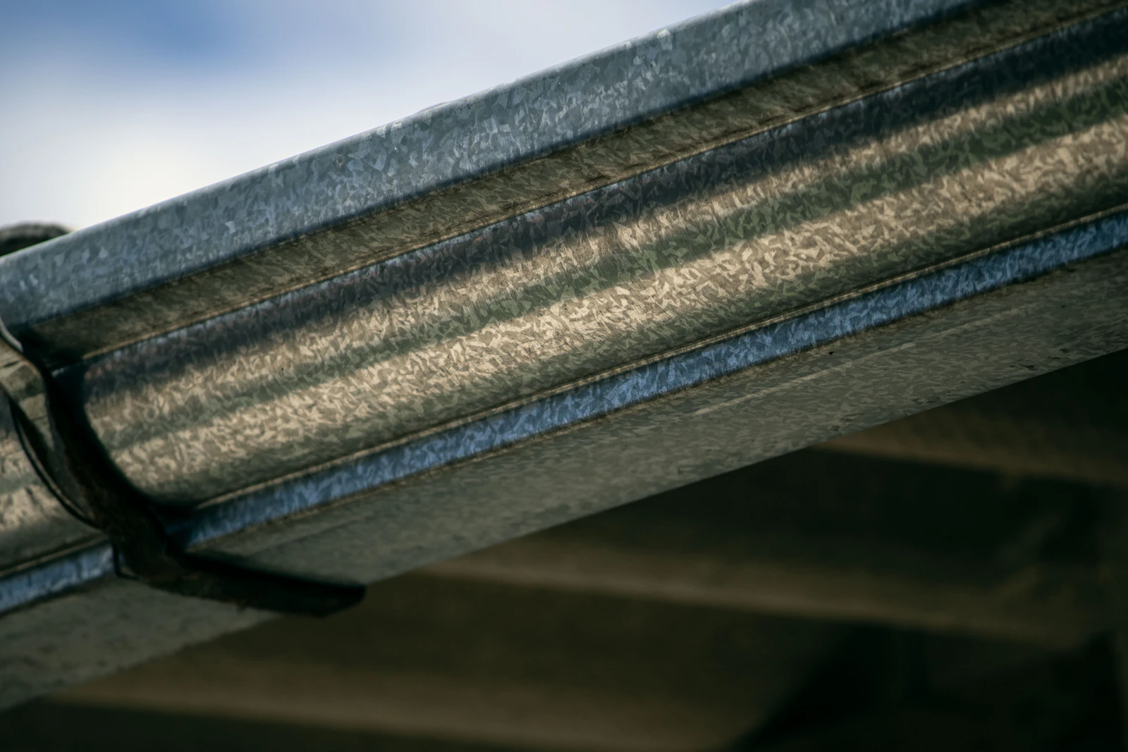 Close view of a galvanised gutter profile and visible bracket