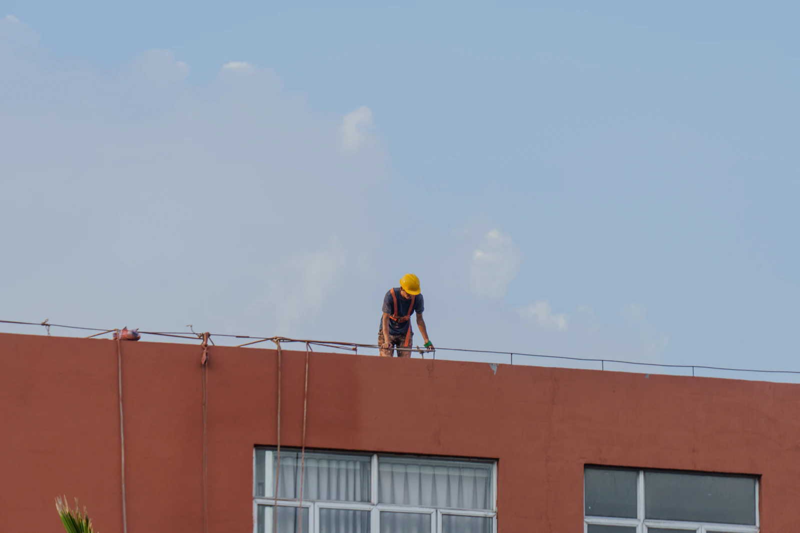 Worker wearing a hard hat and safety harness at roof level